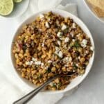 Mexican elote dip in a bowl with lime and chips
