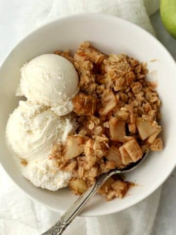 air fryer apple crisp in bowl with ice-cream.