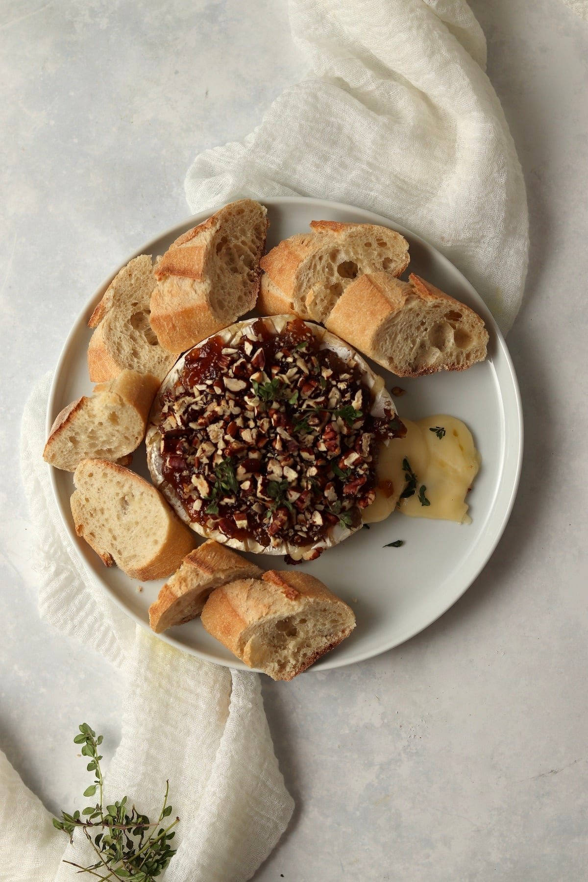 Melty Baked Brie with jam on a plate with thyme.