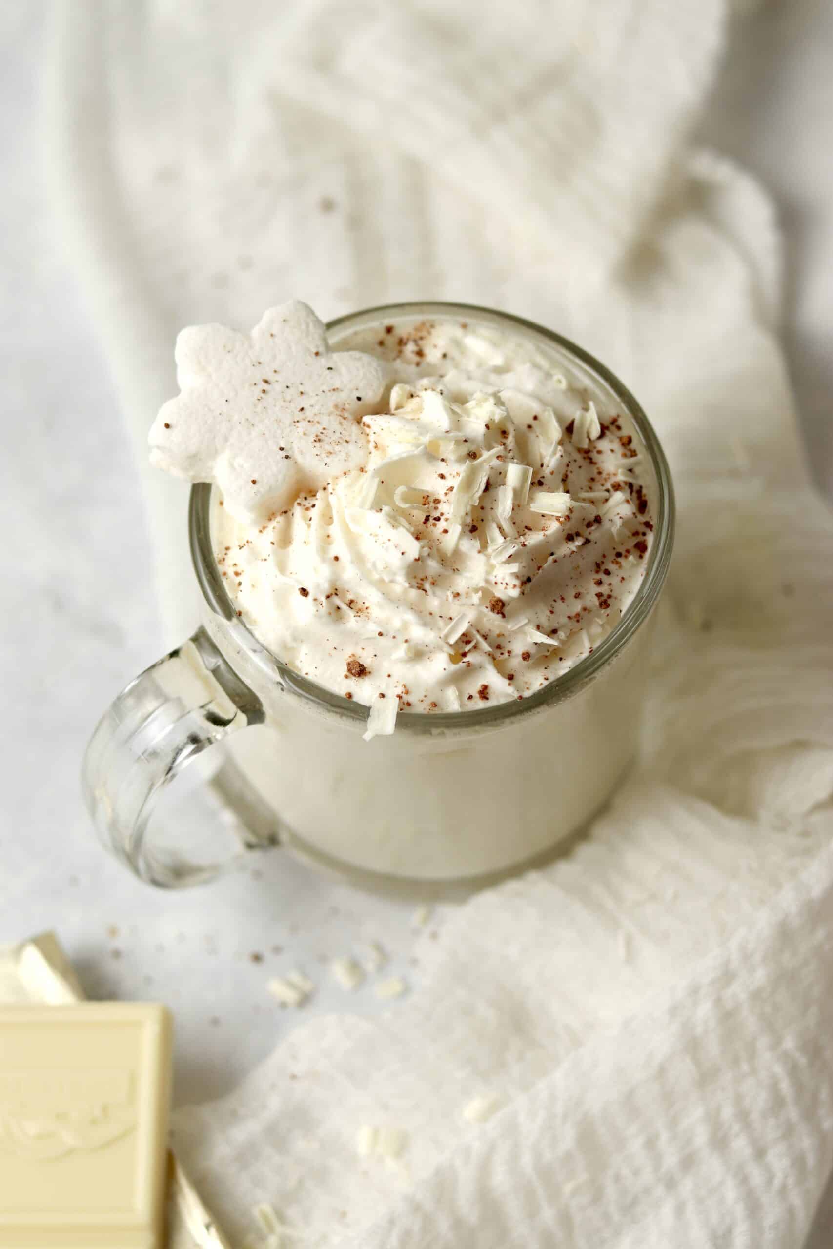 Copycat Starbucks White Hot Chocolate in a glass mug with whipped cream.