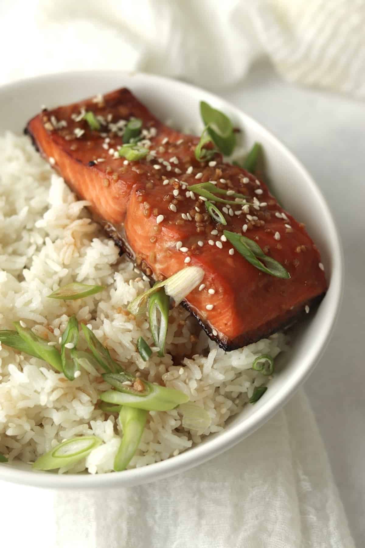 Honey garlic salmon over white rice with green onions.