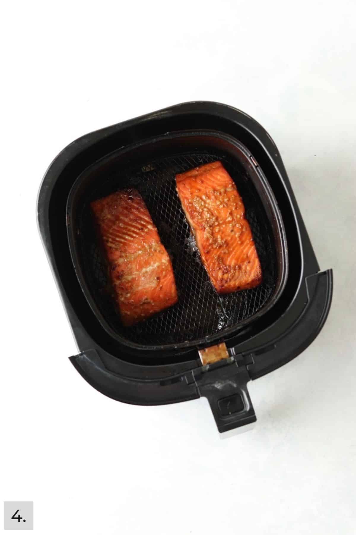 Two cooked honey garlic salmon filets in air fryer.
