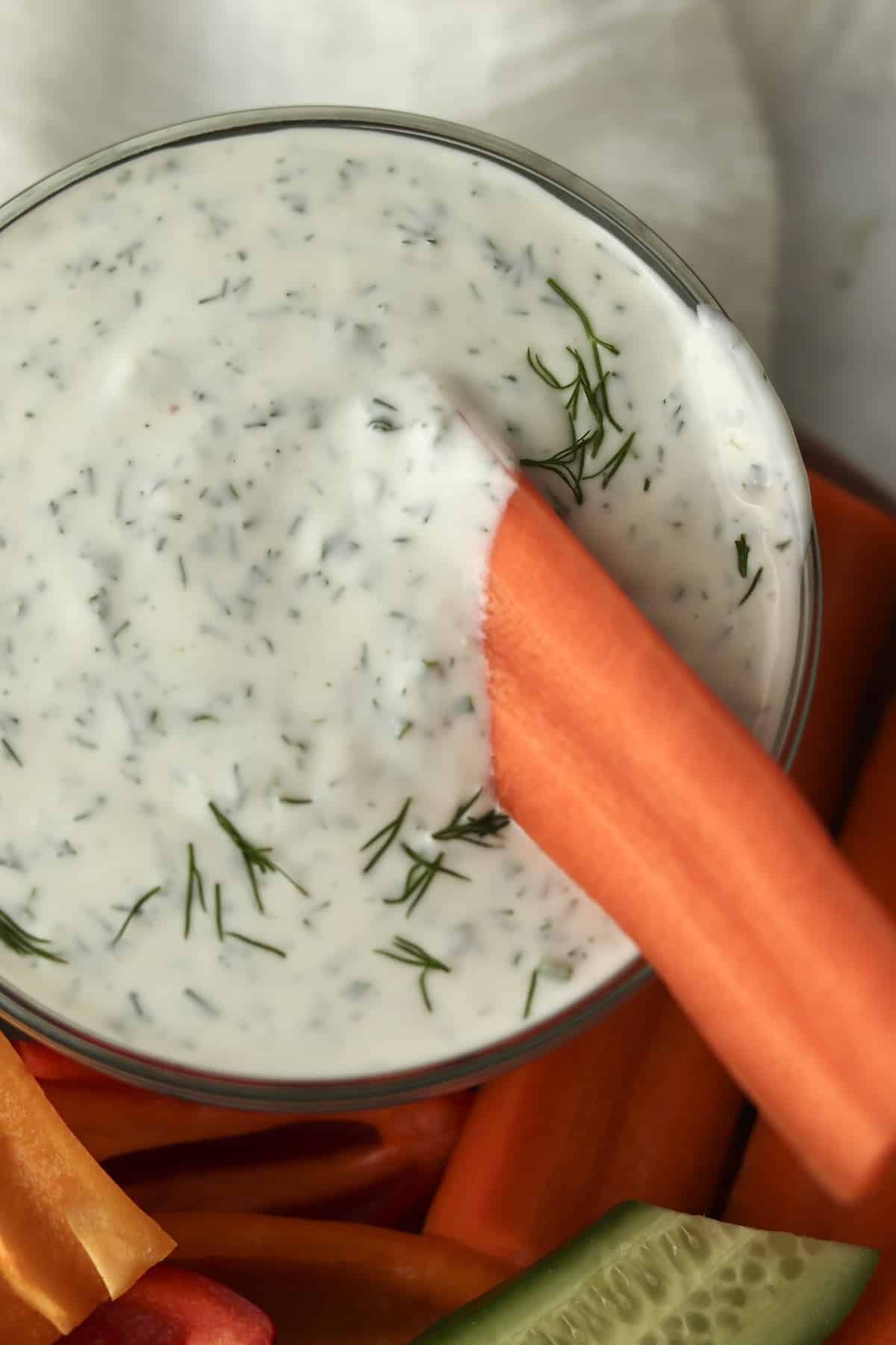 Carrot stick being dipped into ranch dressing.