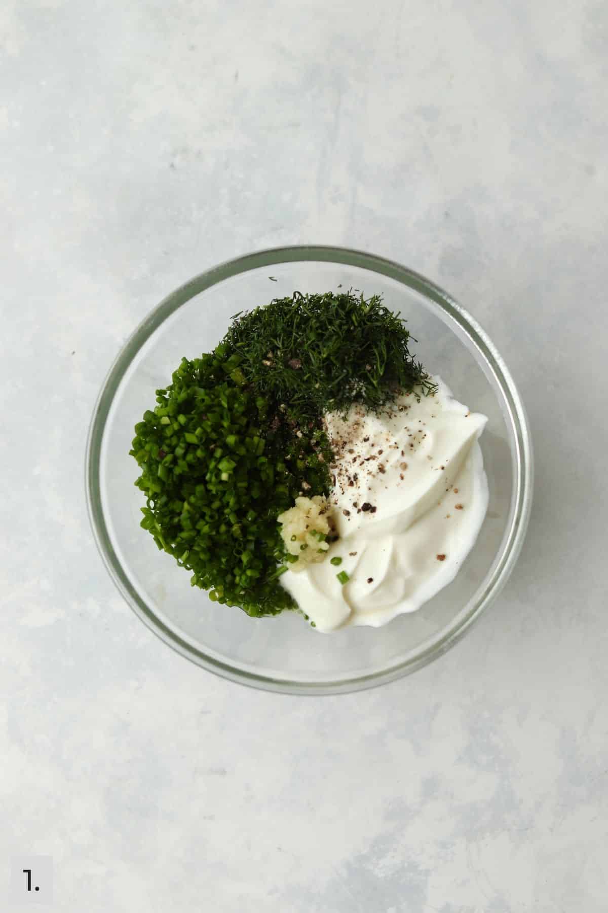 Greek yogurt, dill, chives, and garlic in glass bowl.