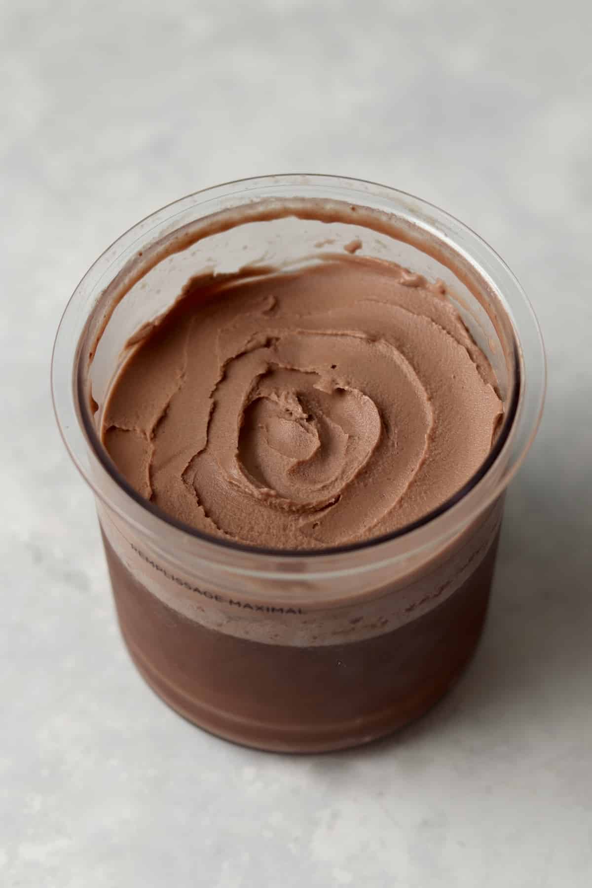 Creamy chocolate soft serve ice cream in a Ninja Creami plastic pint container.