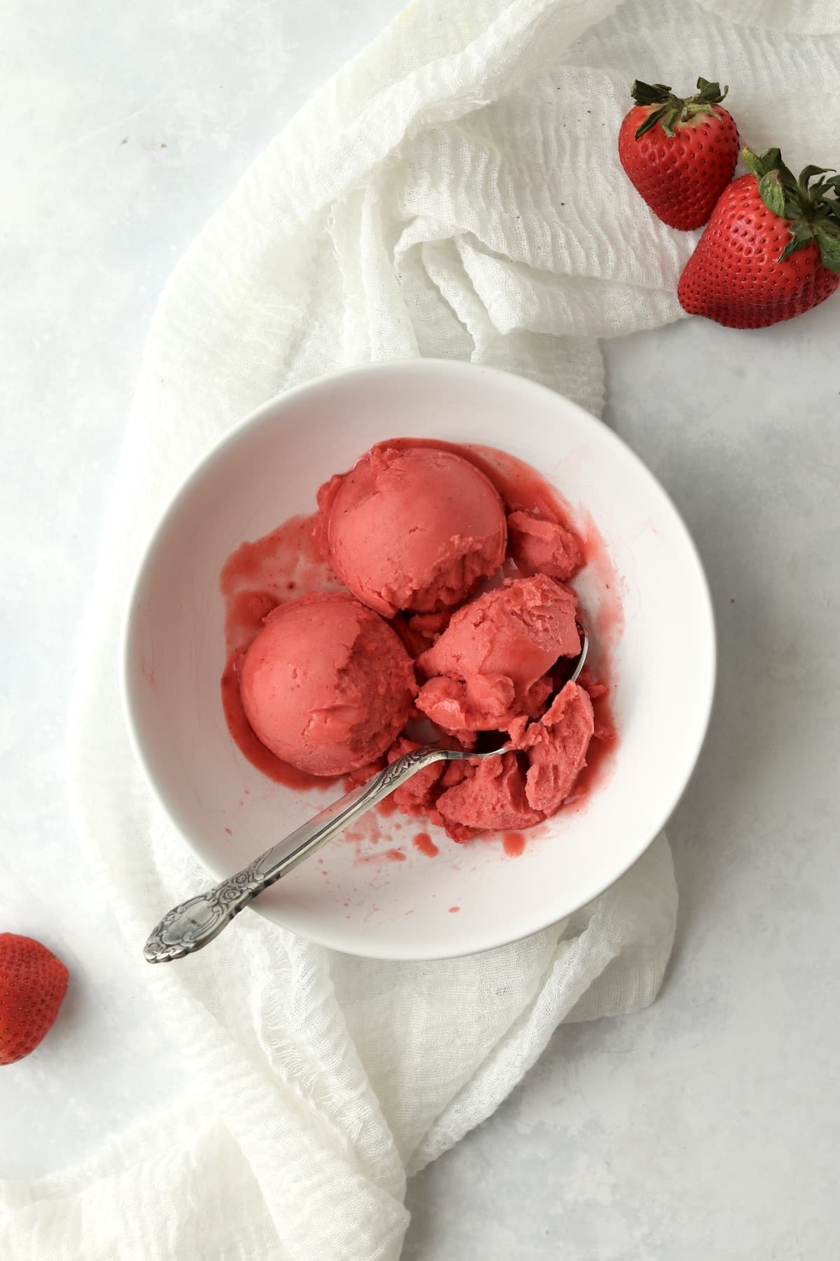 Ninja Creami Strawberry Sorbet scooped in a bowl with fresh strawberries.