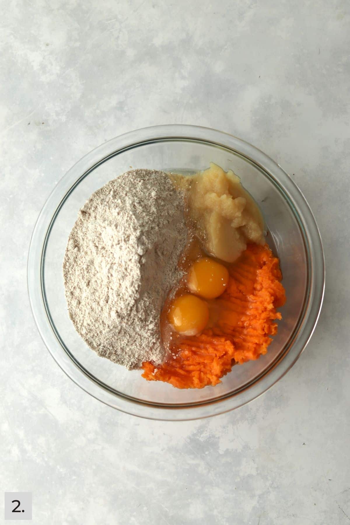 Mashed sweet potato, flour, eggs, and applesauce in a mixing bowl.