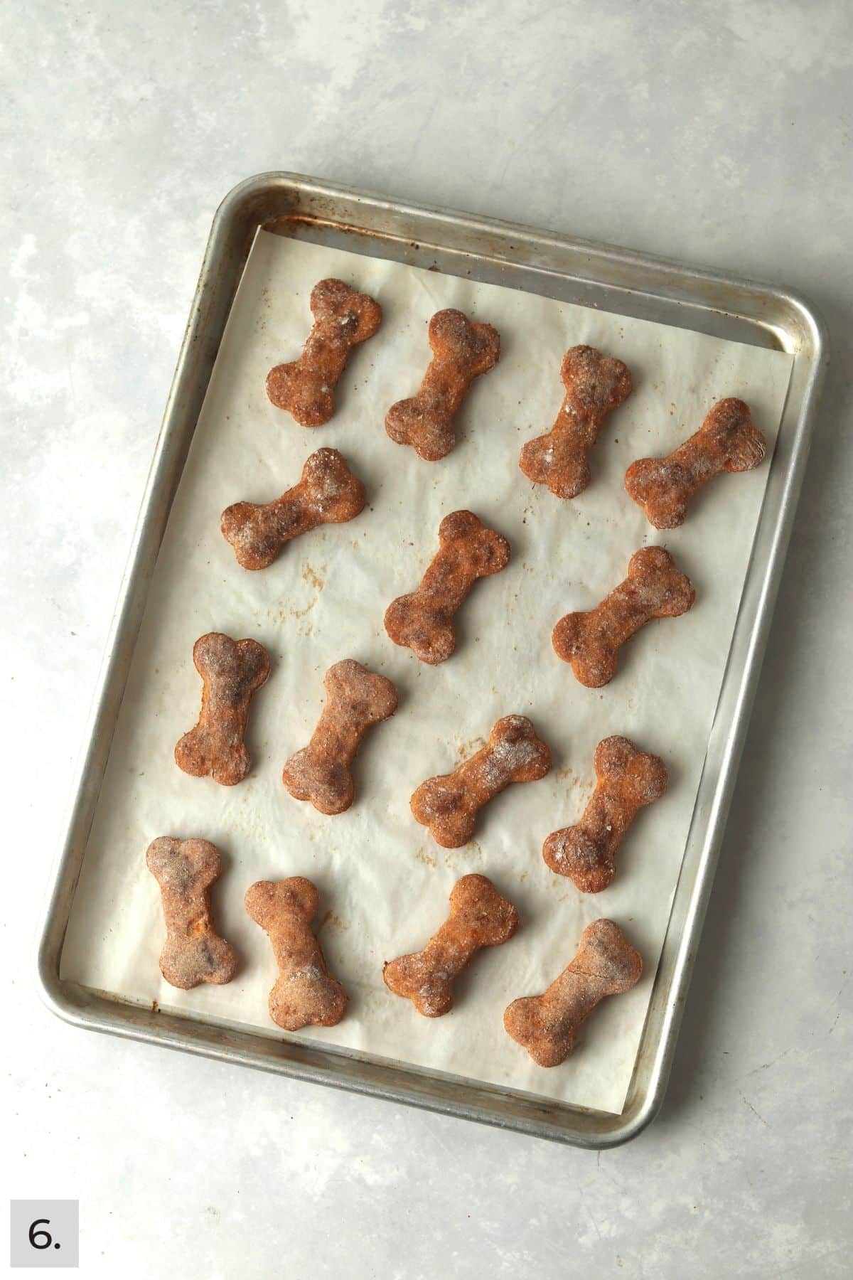 Baked sweet potato dog treats cut into bone shapes on a baking sheet.