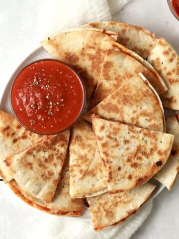 Plate of pizza quesadillas with marinara and pepperoni.