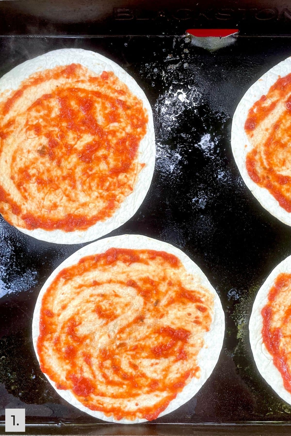 Tortillas on the Blackstone griddle with a thin layer of marinara sauce.