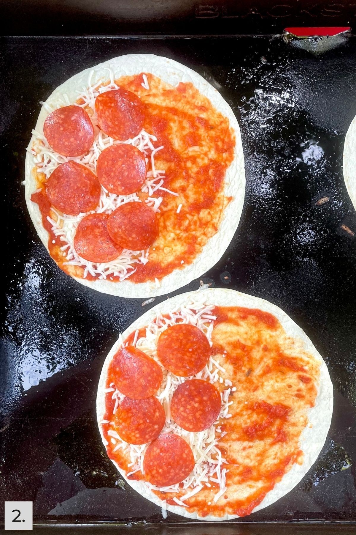 Tortillas with marinara sauce, shredded cheese, and pepperoni slices on the griddle.