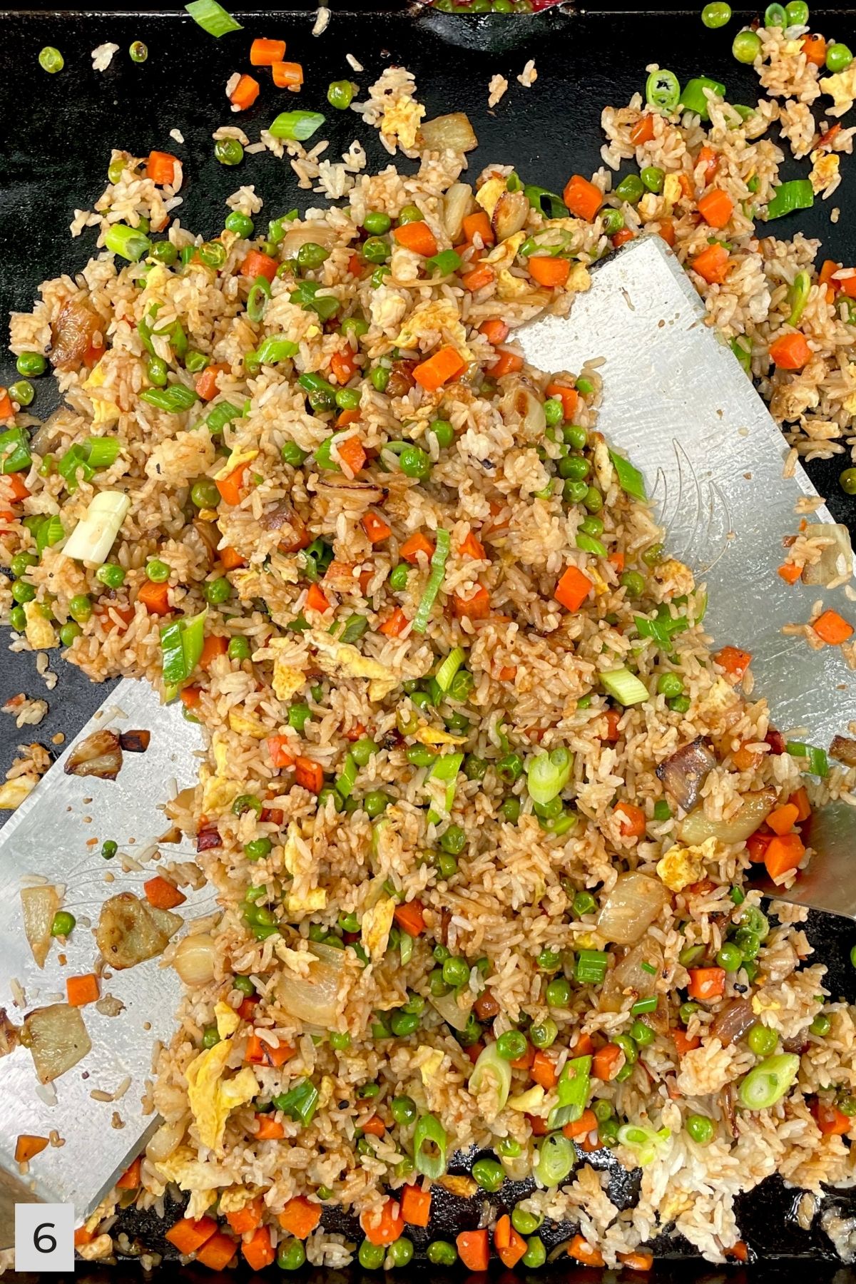 Finished Veggie Fried Rice on Blackstone with two metal spatulas..