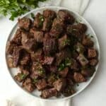 Blackstone Garlic Butter Steak Bites on a plate with parsley.