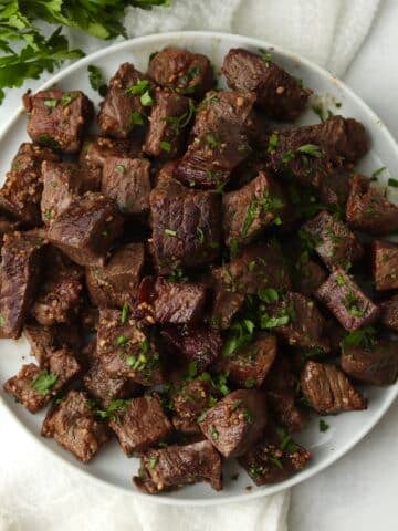 Blackstone Garlic Butter Steak Bites on a plate with parsley.