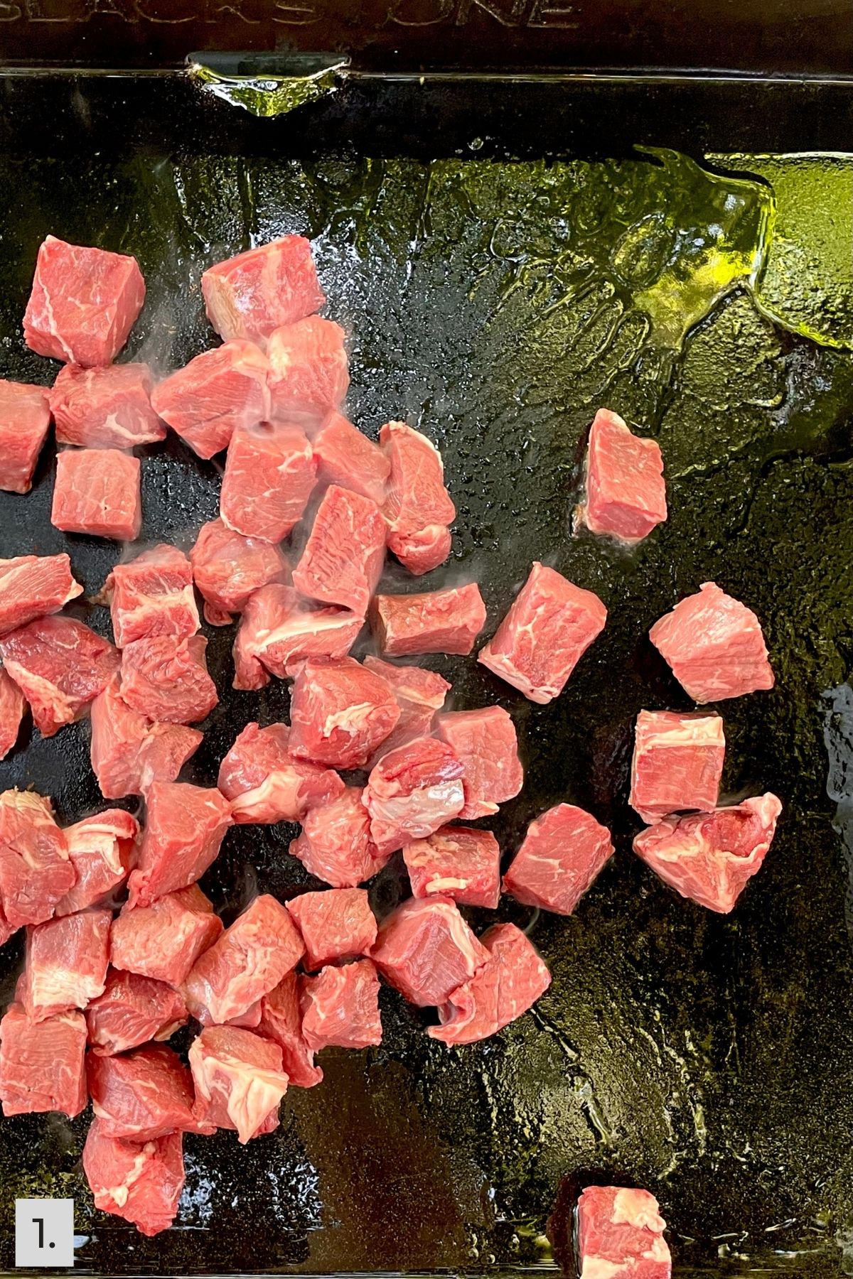 Uncooked steak bites on Blackstone griddle.