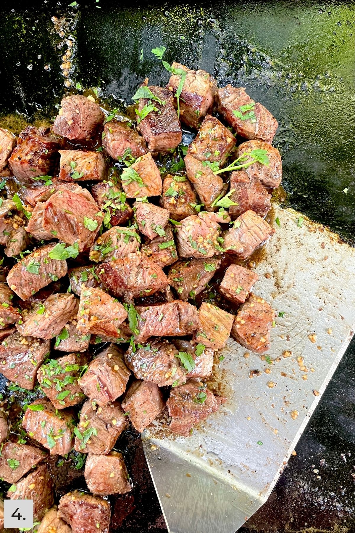 Garlic Butter Steak Bites being tossed with parsley on Blackstone.