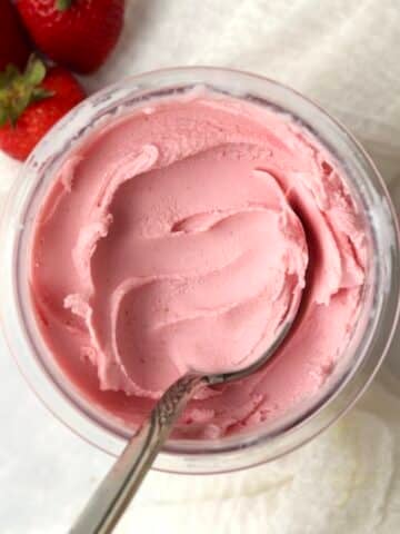 Ninja Creami Strawberry Frozen Yogurt in the pint container with fresh strawberries.