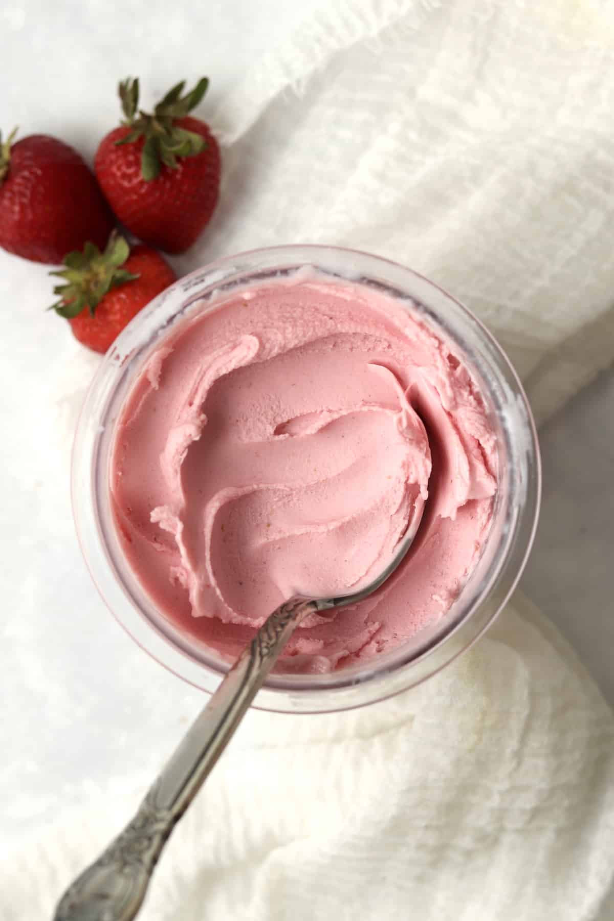 Ninja Creami Strawberry Frozen Yogurt in the pint container with fresh strawberries.