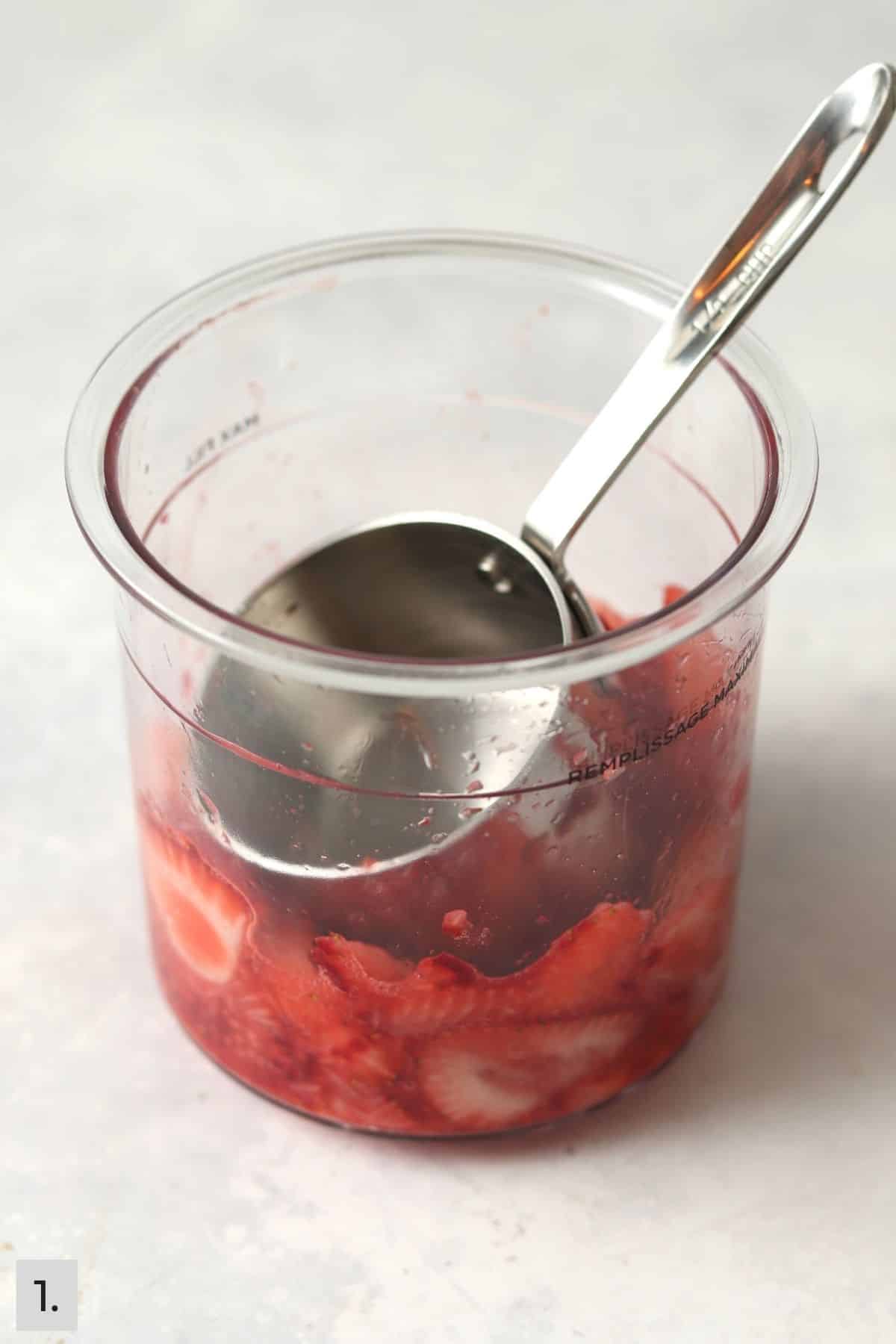 Strawberries being mashed into Ninja Creami pint container.