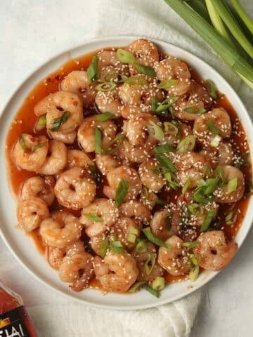 Firecracker shrimp in the sauce on a plate with green onions.