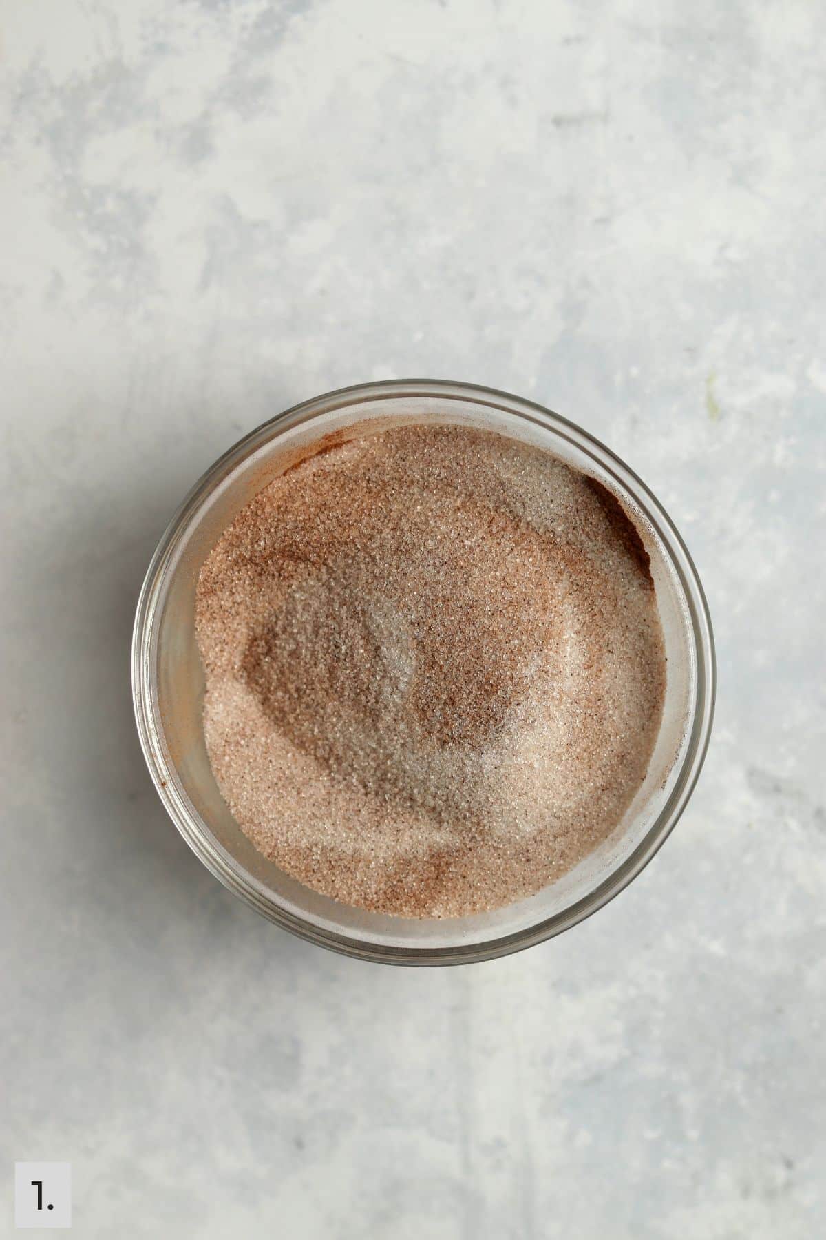 Cinnamon sugar being mixed in glass bowl.