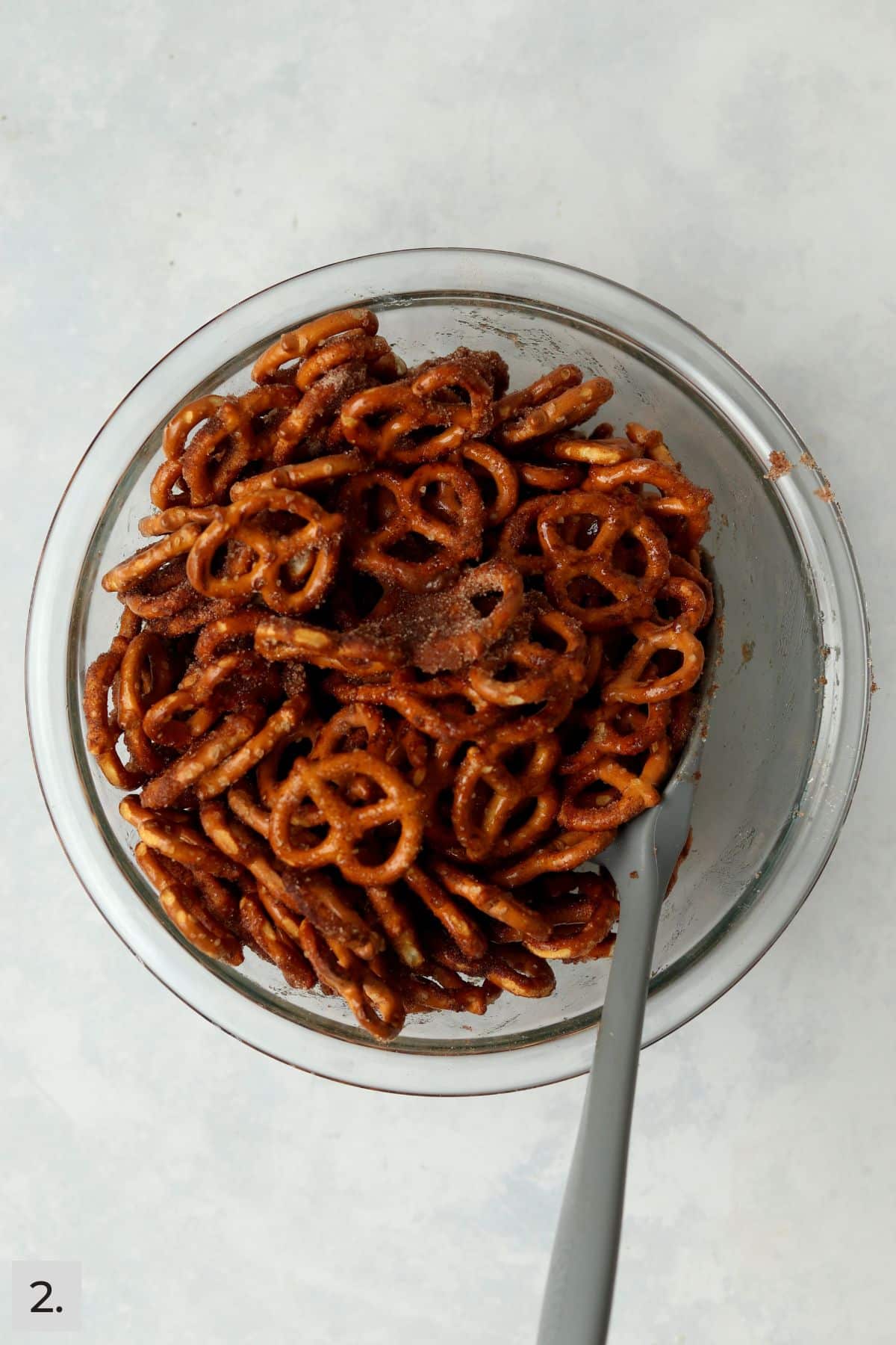 Pretzels tossed with butter and cinnamon sugar in a mixing bowl.