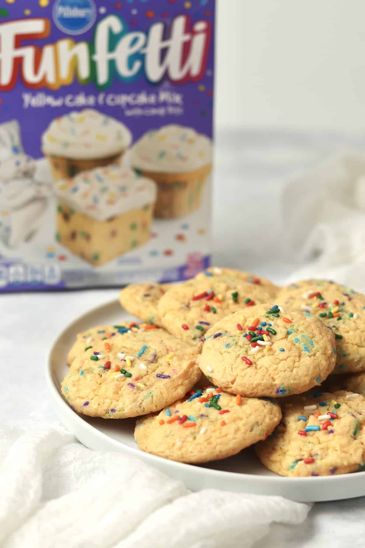 Plate of funfetti cookies with a box of funfetti cake mix in background.