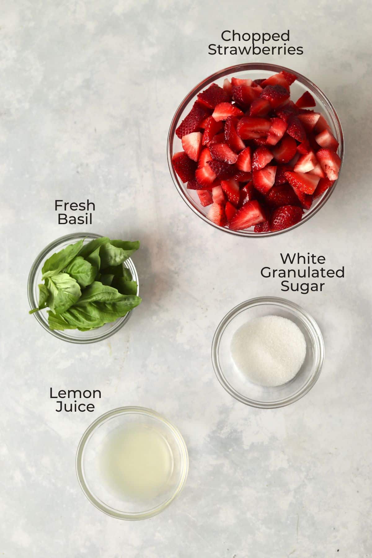 Fresh strawberries, fresh basil, sugar, and lemon juice in glass prep bowls.