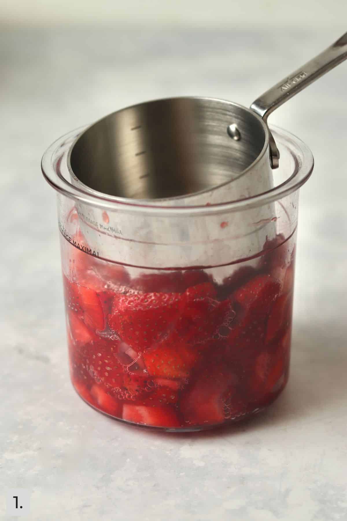 Strawberries being mashed in pint container.