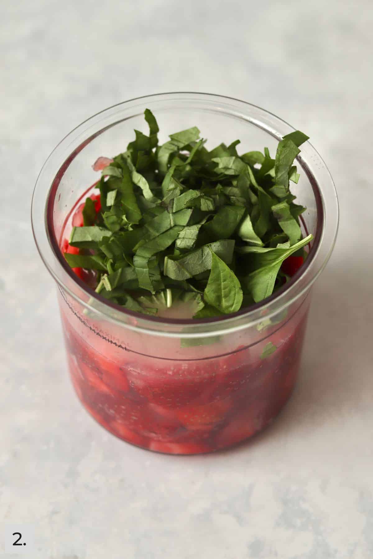 Fresh basil added to strawberries in Ninja Creami pint container.