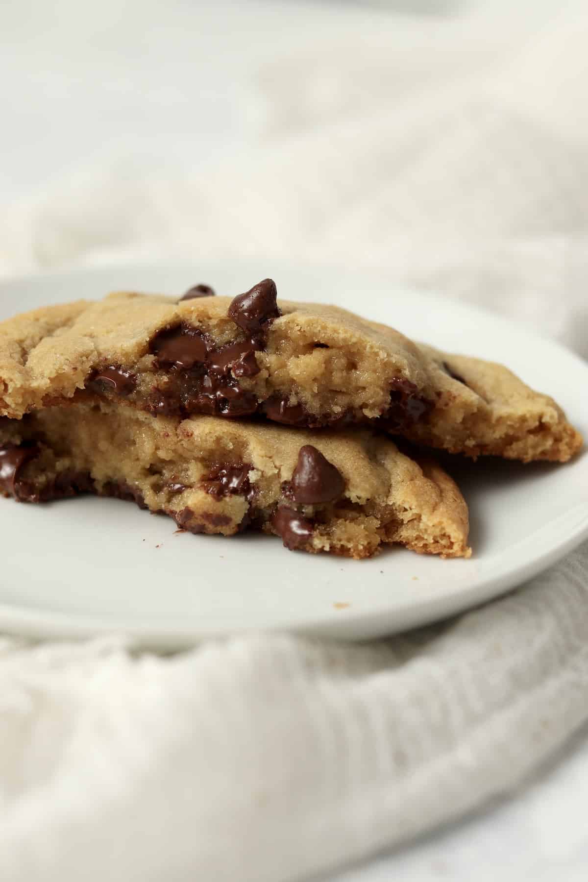 A large single serve chocolate chip cookie broken in half to show the tender inside.