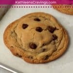 Two large chocolate chip cookies on a baking sheet.