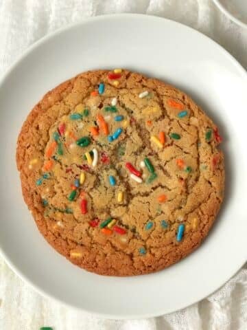 Single serve sugar cookie on a plate with sprinkles.