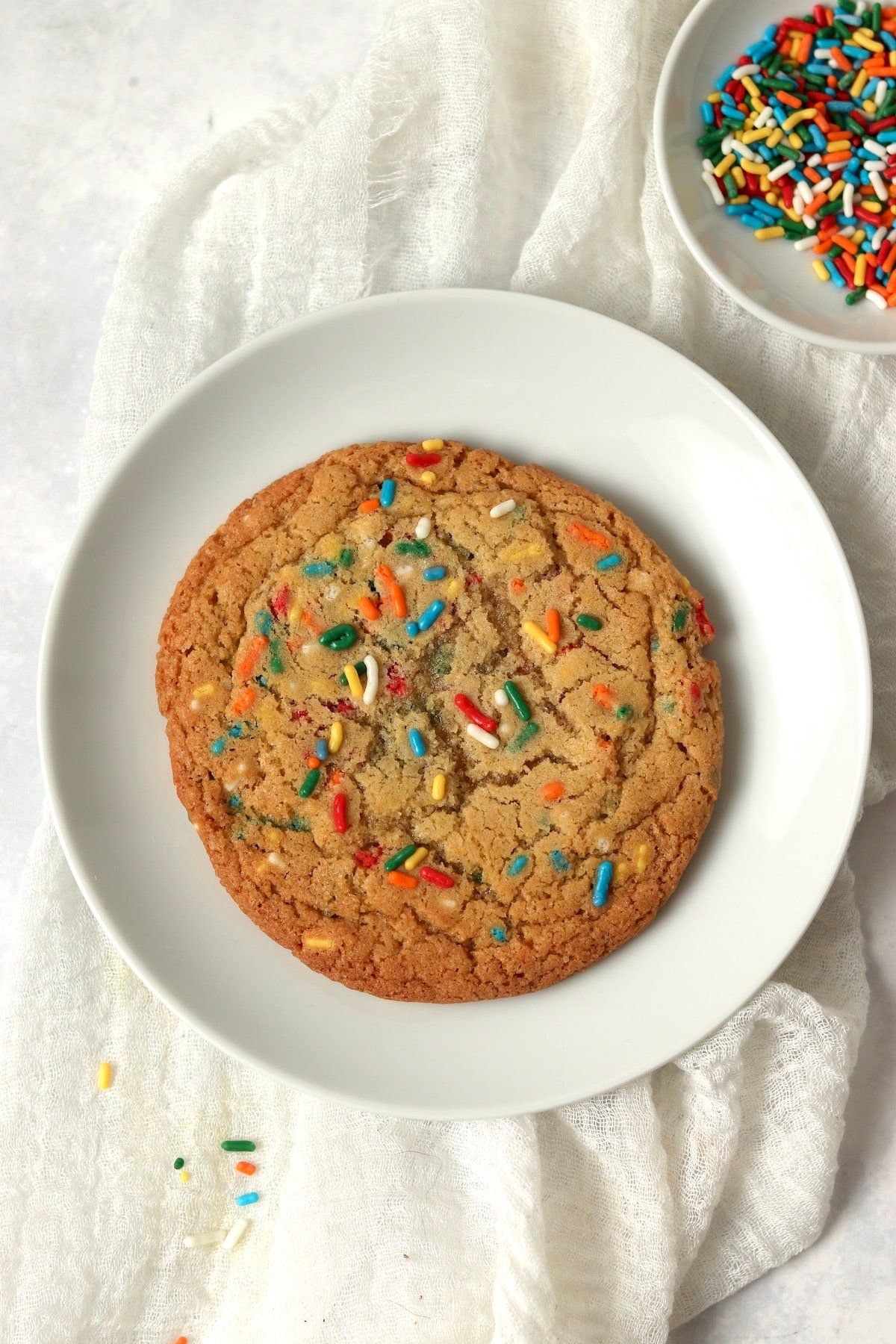 Single serve sugar cookie on a plate with sprinkles.