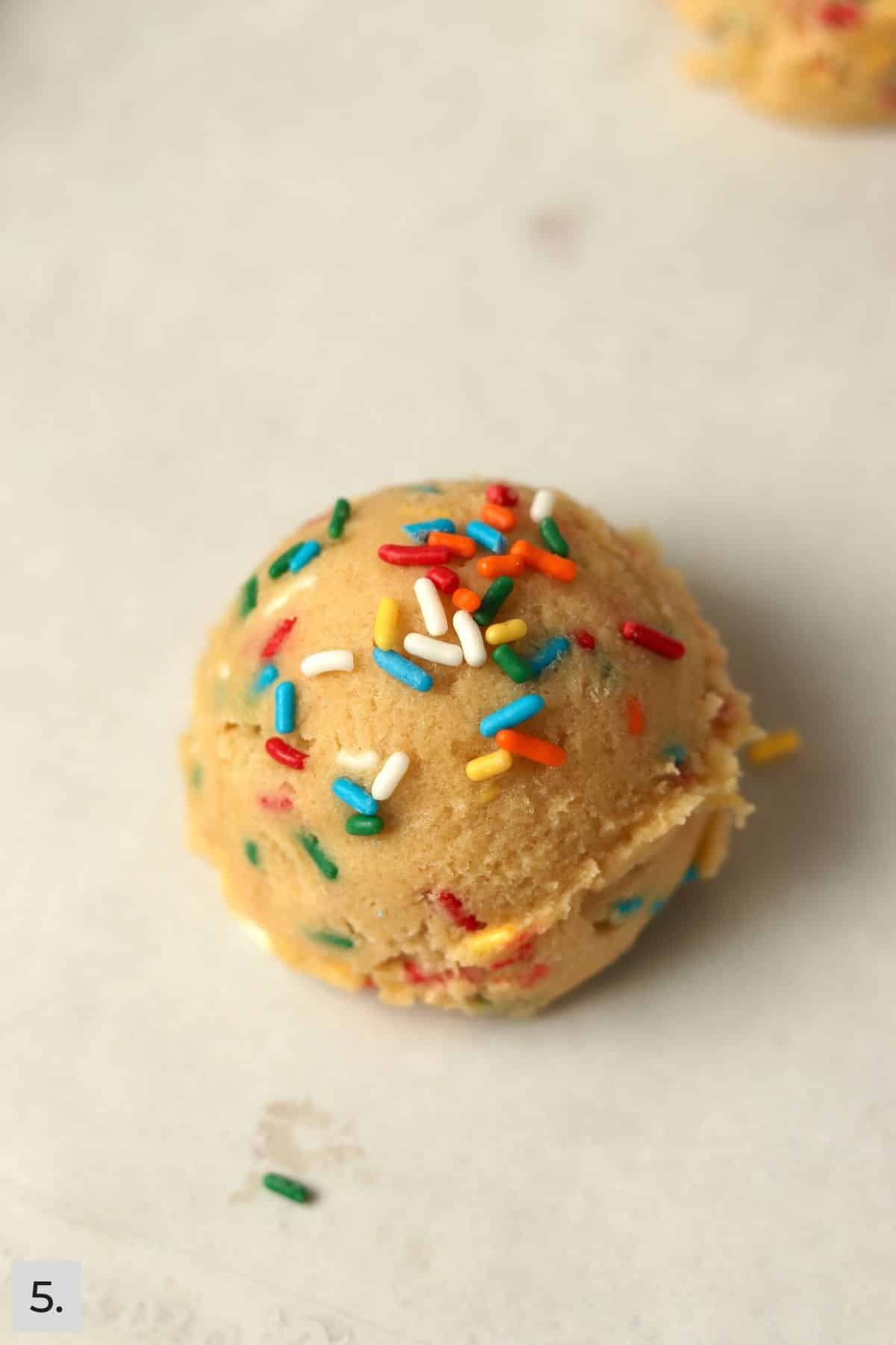 Single serve sugar cookie dough ball on a baking sheet.