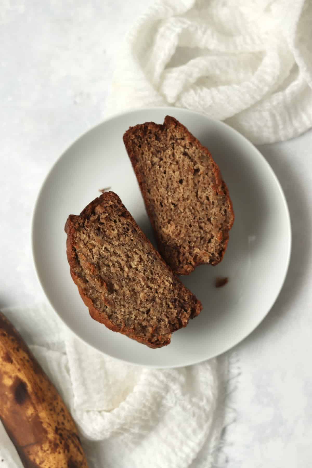 Single serve banana bread cut in half to show tender inside.