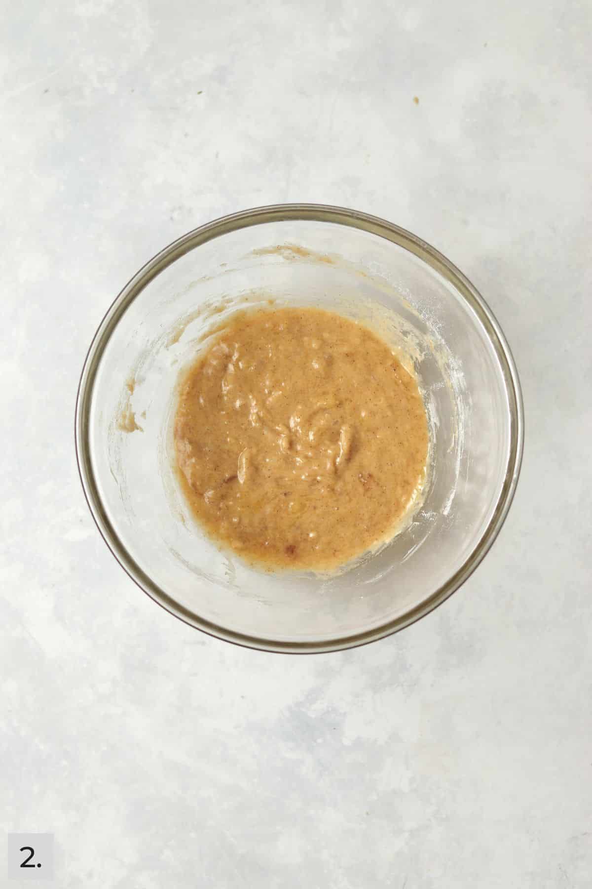 Banana bread batter in a glass mixing bowl.