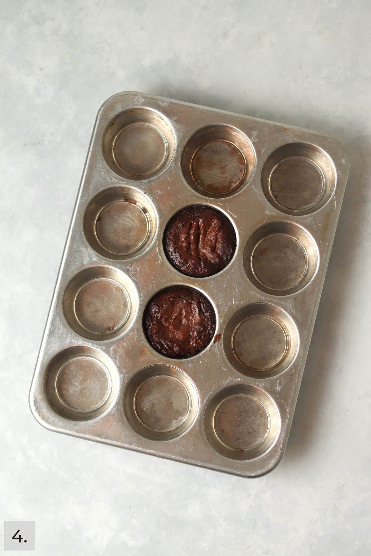 Two individual brownies baked in a muffin pan.