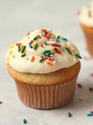 Single serve vanilla cupcake with sprinkles on top.