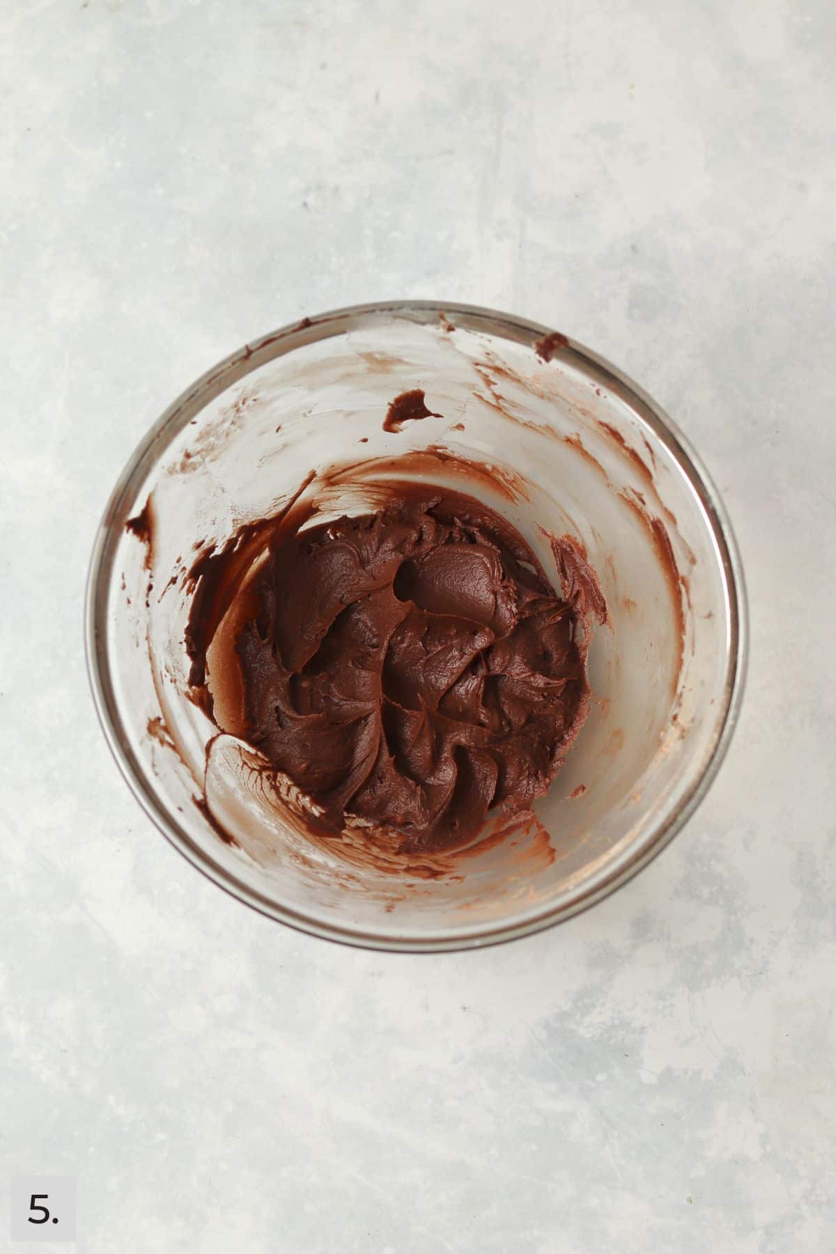 Small batch of chocolate frosting in a glass bowl.