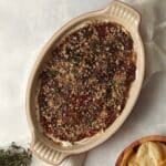 Goat Cheese and Fig Dip in a dish topped with thyme and pecans.