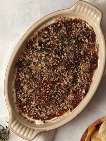 Goat Cheese and Fig Dip in a dish topped with thyme and pecans.