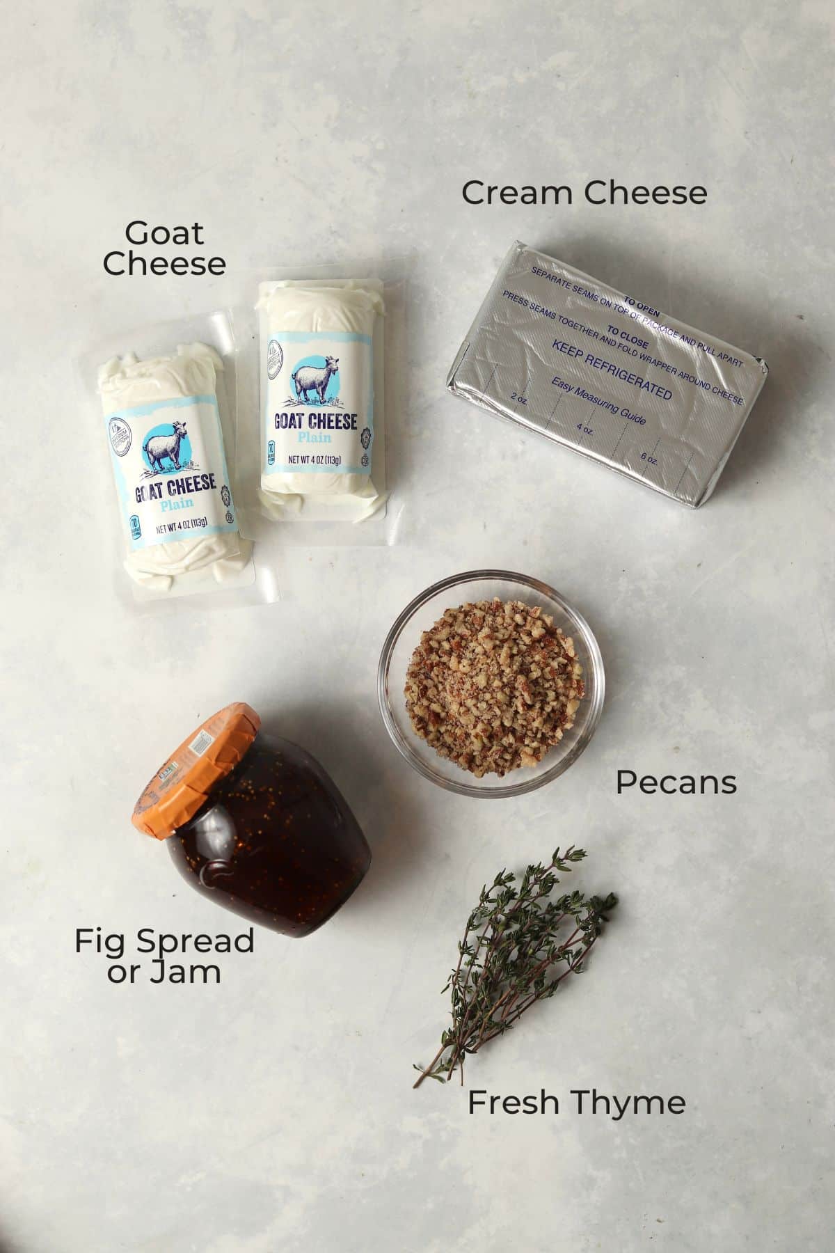 Cream cheese, goat cheese, fig spread, pecans, and thyme spread out as ingredients.