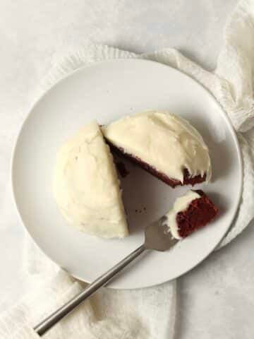 Single serve red velvet cake with cream cheese frosting on a small plate.