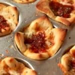 5 Ingredient pizza cups with pepperoni in the muffin pan.