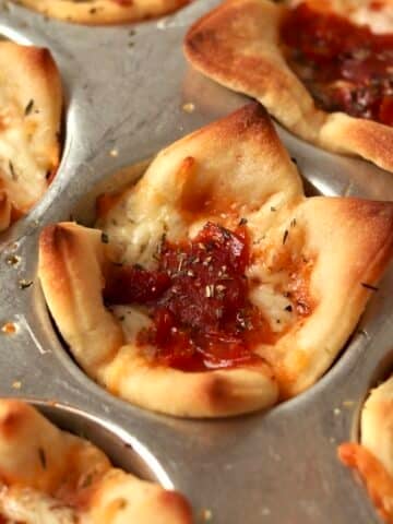 5 Ingredient pizza cups with pepperoni in the muffin pan.