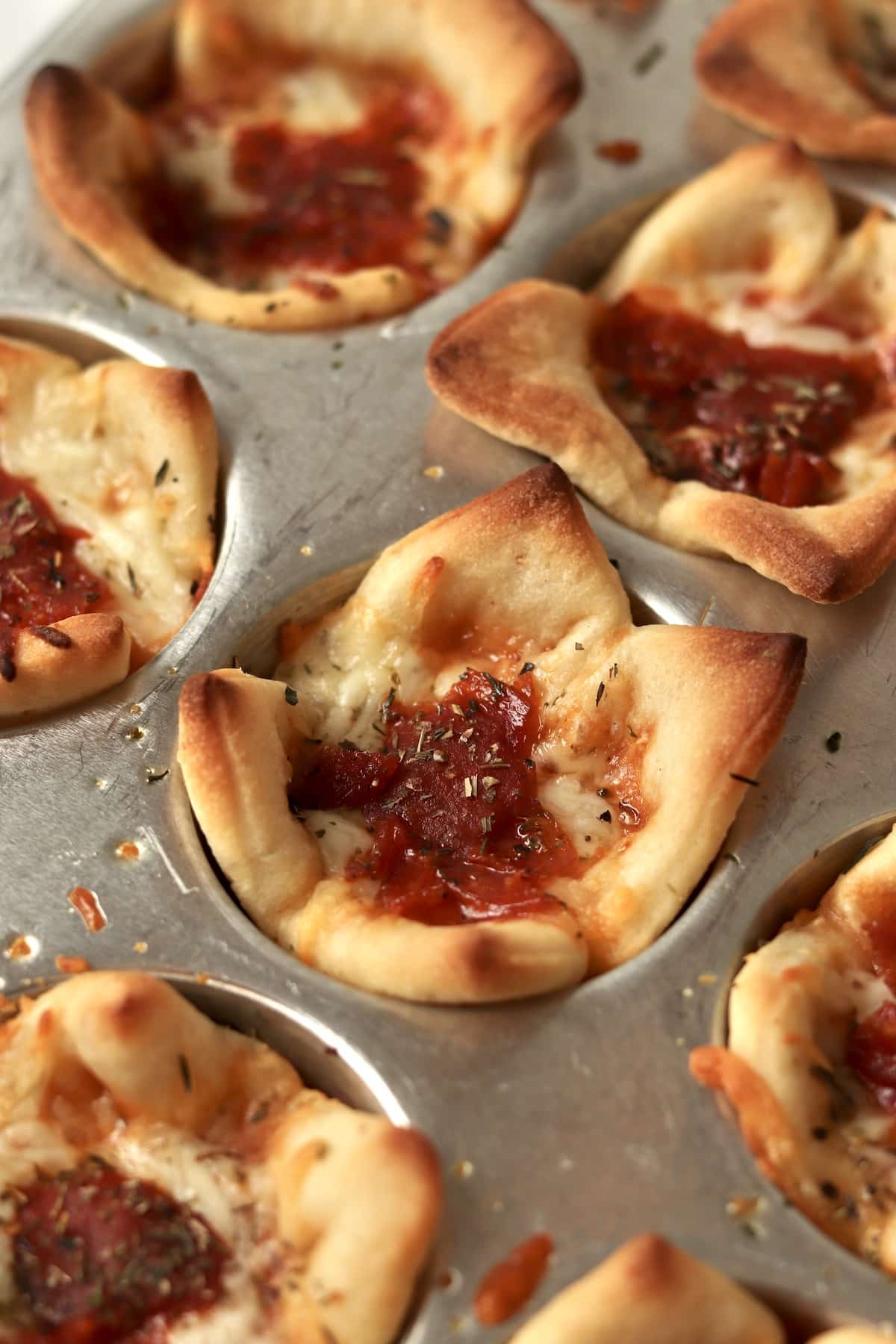 5 Ingredient pizza cups with pepperoni in the muffin pan.