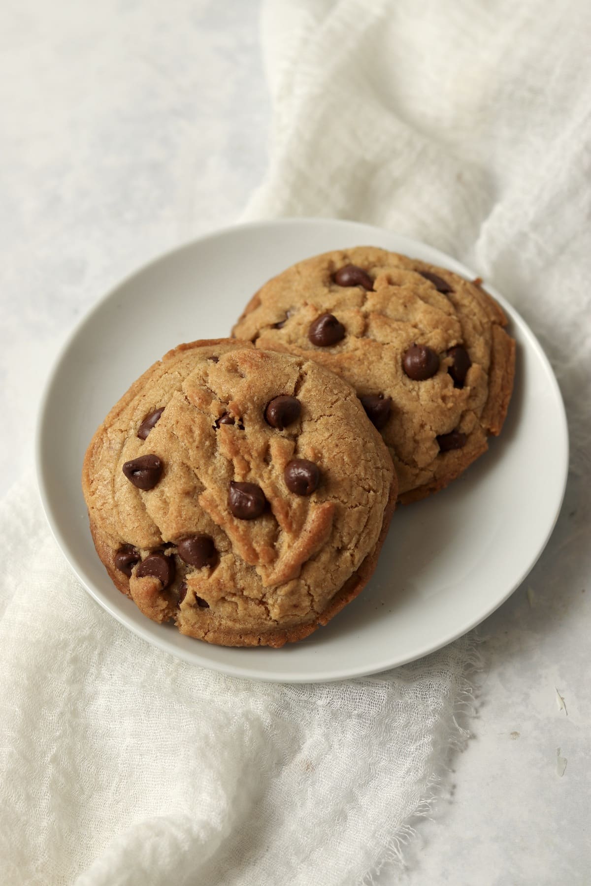 Two brown butter chocolate chip cookies on a plate.