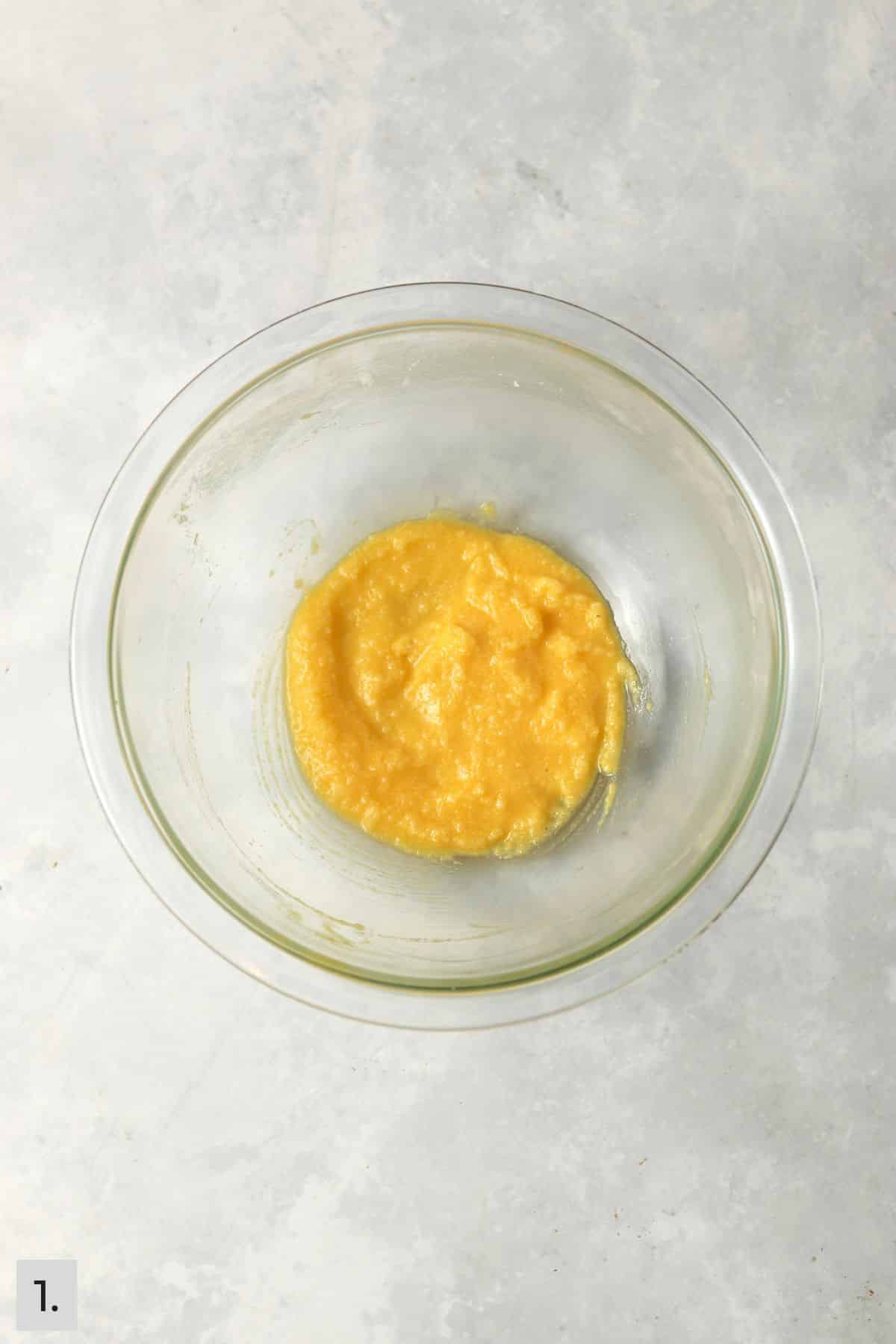 Butter, sugar, egg yolk, and vanilla mixed together in a glass bowl.