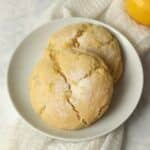 Two lemon cookies on a plate with a fresh lemon in background.